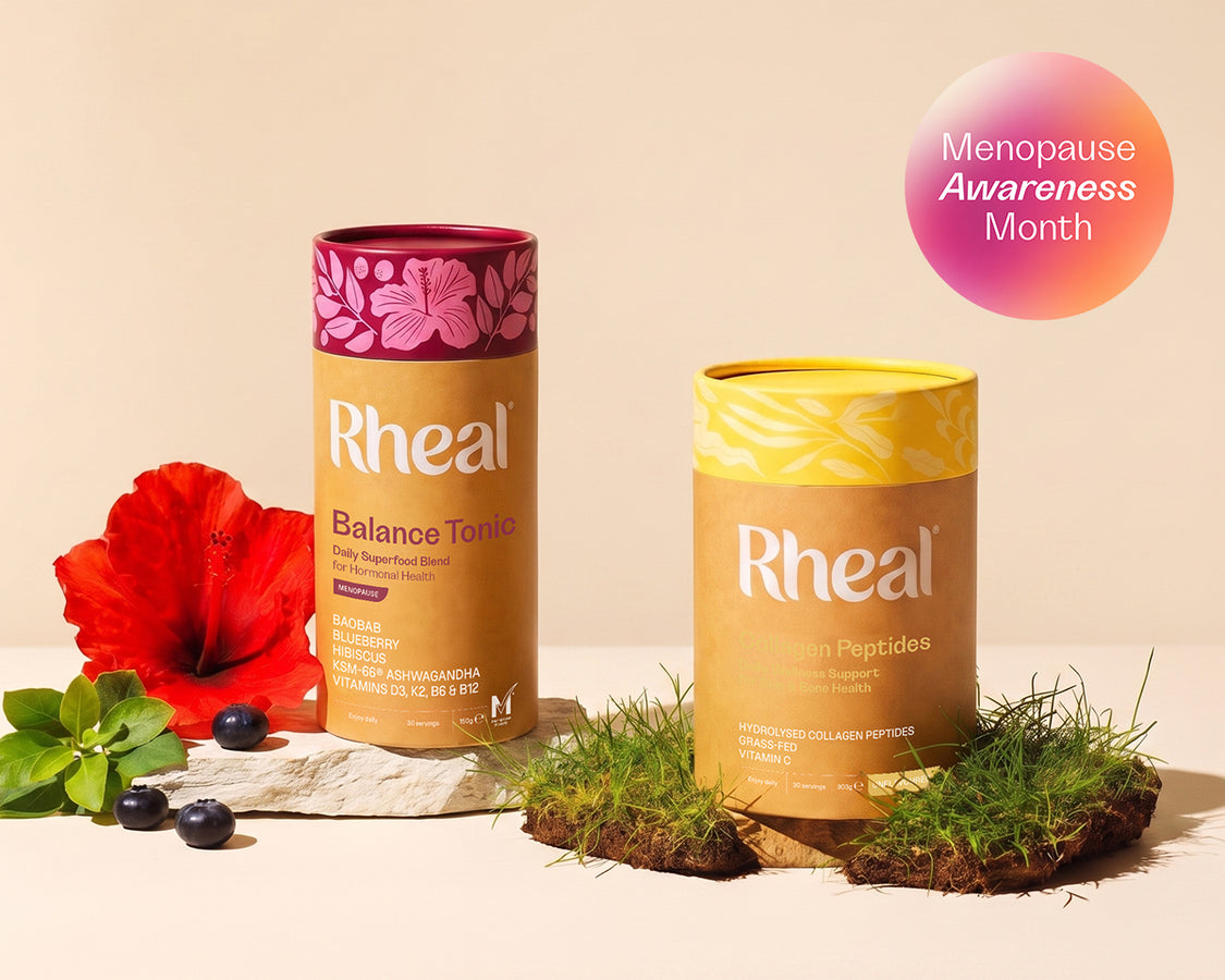 Rheal Balance Tonic Menopause and Rheal Collagen tubs surrounded by hibiscus, blueberries and moss